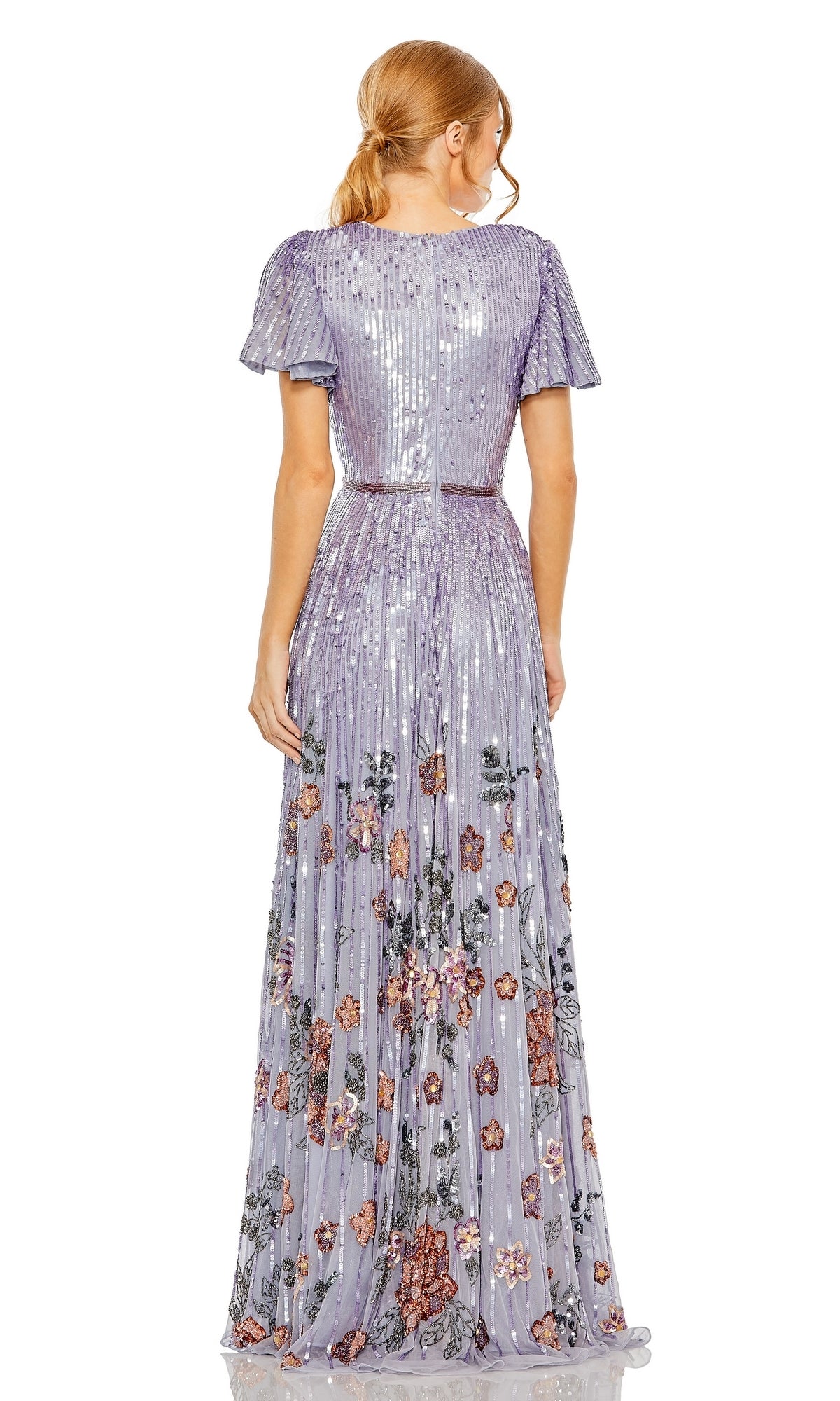 A red-haired woman in a ponytail is seen from behind wearing the Long Formal Dress 5637 by Mac Duggal—a floor-length, short-sleeved lavender sequin gown with a v-neckline and floral embroidery.